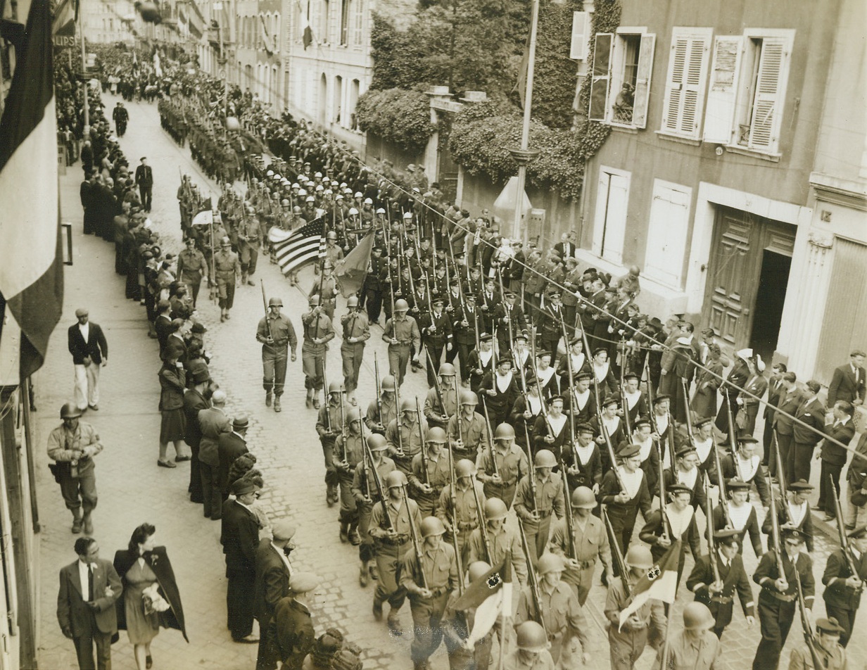 Allied Troops March On Bastille Day, 7/19/1944. France – In close formation American and French troops march side by side through the streets of Cherbourg during Bastille Day celebrations. (Passed by Censors) Credit: ACME photo by Bert Brandt, War Pool Correspondent;