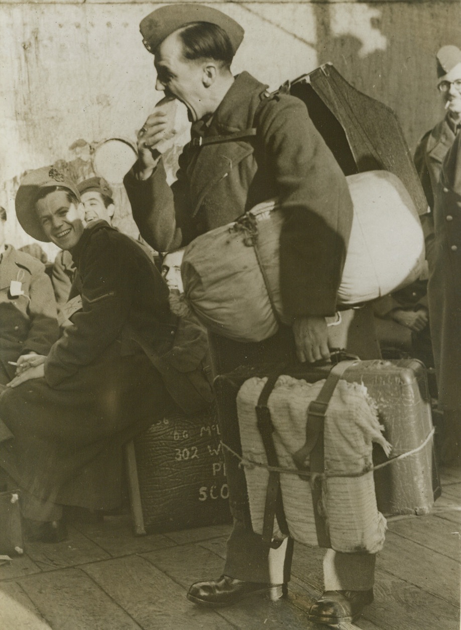 No More Nazi Menus, 11/7/1943. Leith, Scotland -- Before even putting down his luggage, a repatriated Allied prisoner grabs a thick sandwich at Leith, Scotland, where civilians and soldiers interned in Germany recently landed. The Nazi prison diet isn’t conducive to weight-gaining. This hungry soldier is L/Cpl. William Gibson, of Aberdeen, Scotland, who arrived with the first batch of 3,694 persons, including 104 civilians. Credit: ACME;
