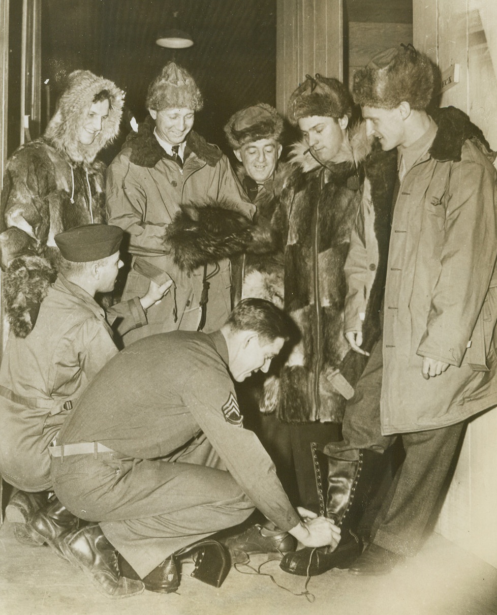 Warm Clothes for Cold Trip, 12/29/1943. Somewhere in Alaska -- Ready to tour Alaskan and Aleutian bases to put on exhibition games for our boys up there, these major league diamond stars get outfitted with heavy, warm clothing for their cold trip. Kneeling, Lt. Arthur Tober (left) of Bridgeport, Connecticut, adjusts a parka on Fred “Dixie” Walker, while Sgt. John A. Theoboldt of Monterey, California, fits a pair of shoepacks to Hank Borowy. Left to right, the baseball players are Stan Musial of the St. Louis Cards; Dixie Walker of the Brooklyn Dodgers; Frankie Frisch, manager of the Pittsburgh Pirates; Danny Ditwhiler of the Cards; and Hank Borowy of the New York Yankees. Credit: ACME;