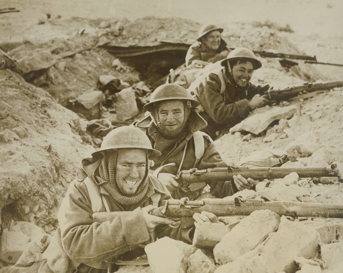 Aided Fall of Bardia, 1/25/41  BARDIA—These smiling Tommies are shown in front line trenches as they aided British forces in battering the Italian desert stronghold of Bardia into submission. This part of the desert wasn’t warm, judging from the heavy coats and mufflers. Credit: ACME.;