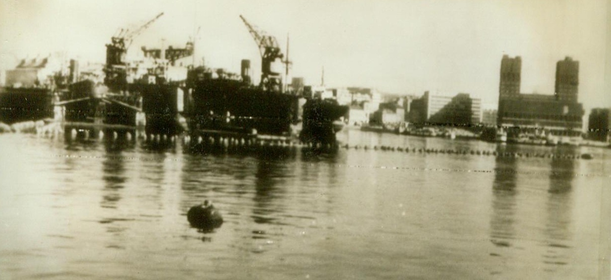 INVASION NIGHTMARES, 5/27/1943. OSLO, NORWAY – Anti- torpedo nets protecting Oslo Harbor are mute testimony that the Nazis fear invasion in Northern Norway. In the background (left) is Akers Machine Factory, the country’s biggest and (right) the Oslo City Hall, taken over by the Germans. Credit (ACME Radiophoto);