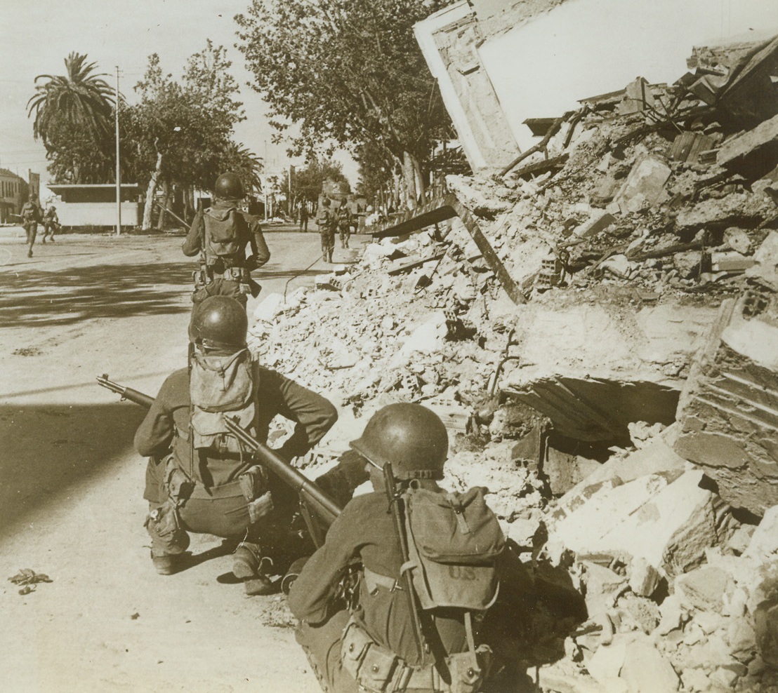 Yanks in Bizerte, 5/26/1943. Bizerte, Tunisia—Crouching beside the ruins of  buildings, a U.S. patrol awaits the order to move forward, while another patrol moves forward to reconnotter. Street to street and house to house fighting took place between Allied and Axis troops before Bizerte became Allied property.Credit: ACME.;