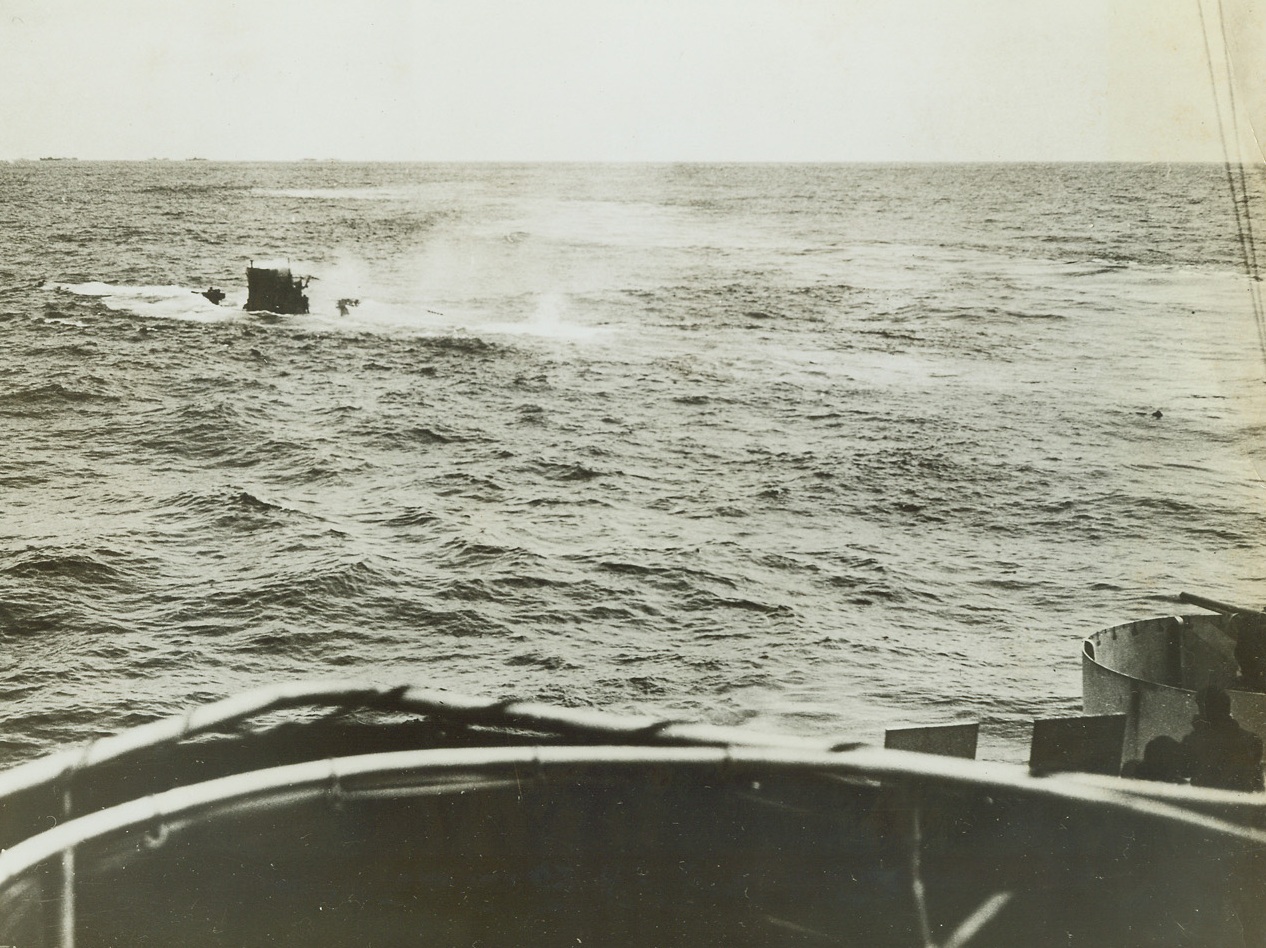 Coast Guard Cutter Sinks Submarine, 5/31/1943. A German submarine attempted to sneak in between a convoy of ships crossing the North Atlantic. Coast Guard Cutters escorting the Merchantmen sighted the U-Boat and The Spencer went into action, aided by The Duane. The Spencer let go a depth charge which brought the sub to the surface; and, then as water rushed into her crushed hull she sank as the Coast Guard picked up her survivors. Bearing down on the sub, The Spencer gets a good look at the sinking sub as she settles in the water. Note the Nazi standing on the deck to the right of the conning tower, and at the right, The Spencer’s gun trained on the U-Boat. A swimming German is barely discernable in the water on the right. Credit: U.S. Coast Guard photo from ACME;