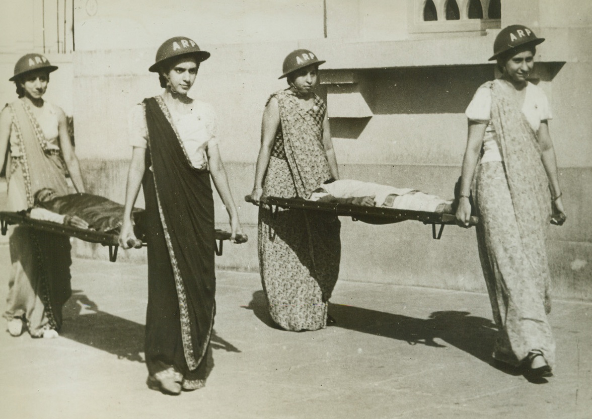 All India Joins In Defense, 2/13/1942. Bombay, India -- …..Just as in other countries, women, too, are training to do their part, and here an air raid precautions glass of Parsee women, members of an ancient Zorastrian sect, practice removing causalities of air raids on stretchers, at the Cusrow Raug class. Credit Line (ACME);