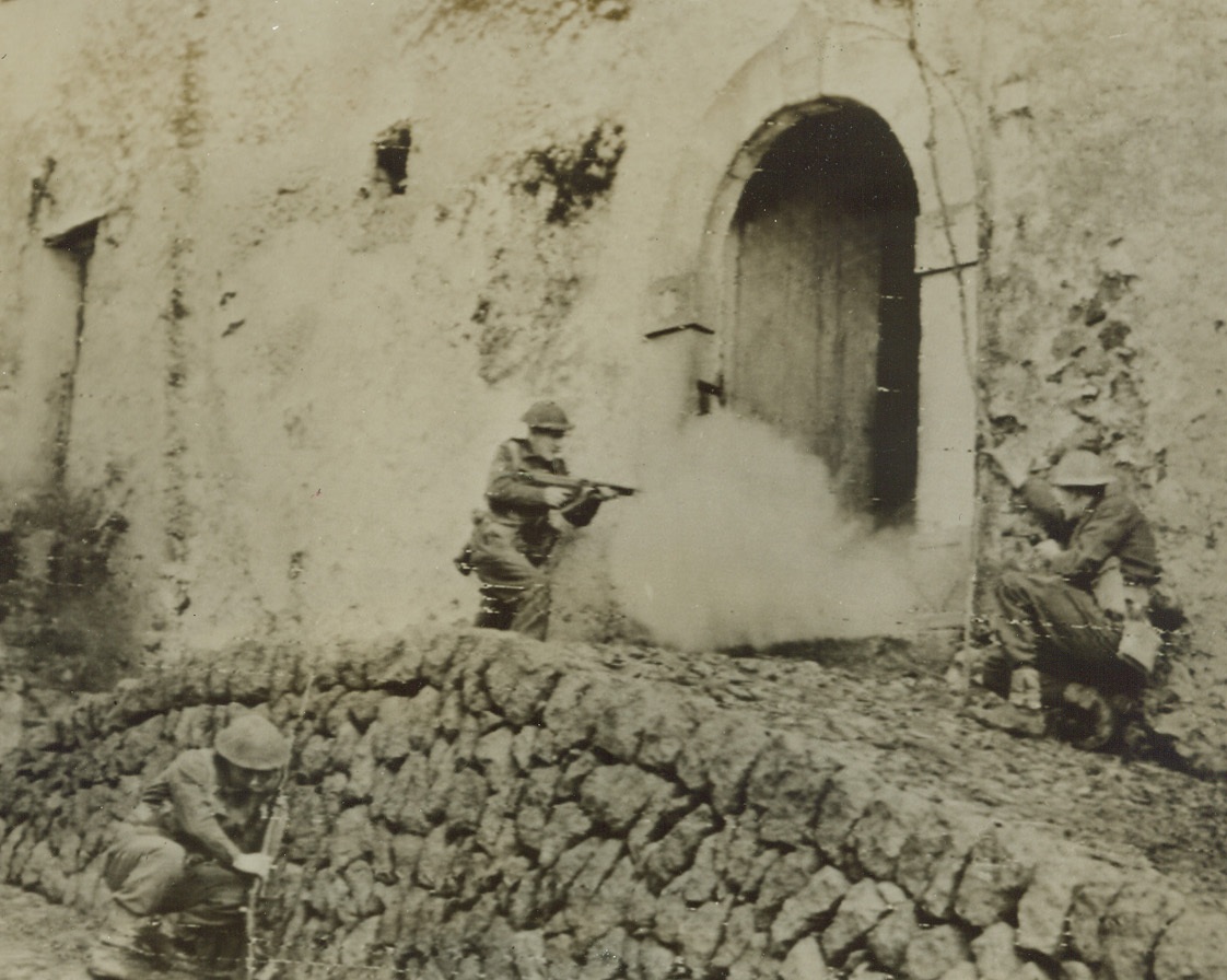 Taking No Chances, 1/28/1944. British soldiers have a “surprise party” in store for any Nazi snipers who may be hiding in this building, “somewhere in Italy.” Their guns on the ready, the Tommies creep up to the doorway, one remaining behind a stone wall in the foreground. Credit: ACME.;