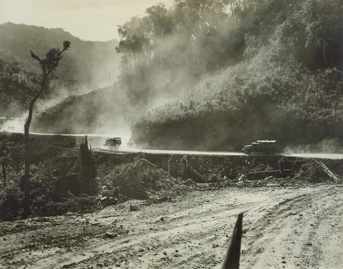 No Concrete Highways Lead to China, 1/25/1944. Burma – Torturous curves, blinding dust and sheared-off embankments plague drivers winding their way into Burma by way of the Ledo Road, “highway” being pushed by American Engineers as fast as Yank and Chinese soldiers can clear the area of Japs. On the offensive since December 26th, Stilwell’s troops are pushing the enemy toward Taihpa Ga.  Credit: ACME photo by Frank Cancellare, War Pool Correspondent;