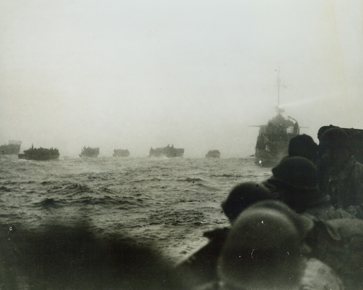 First Photos of Our Attack on Attu, 5/26/1943. As American troops landed on Attu, Aleutian islands, May 11, 1943, a Navy combat photography unit accompanied the first wave of American troops ashore at Japanese-occupied Attu, the Westernmost island of the Aleutian chain.  This photo was made at the start of the attack and shows that landing boats having been put over the side of the transports are beginning to move towards the beach.  The searchlight of the destroyer cuts thru the fog like a pencil.Credit Line (U.S. Navy official photo from ACME;