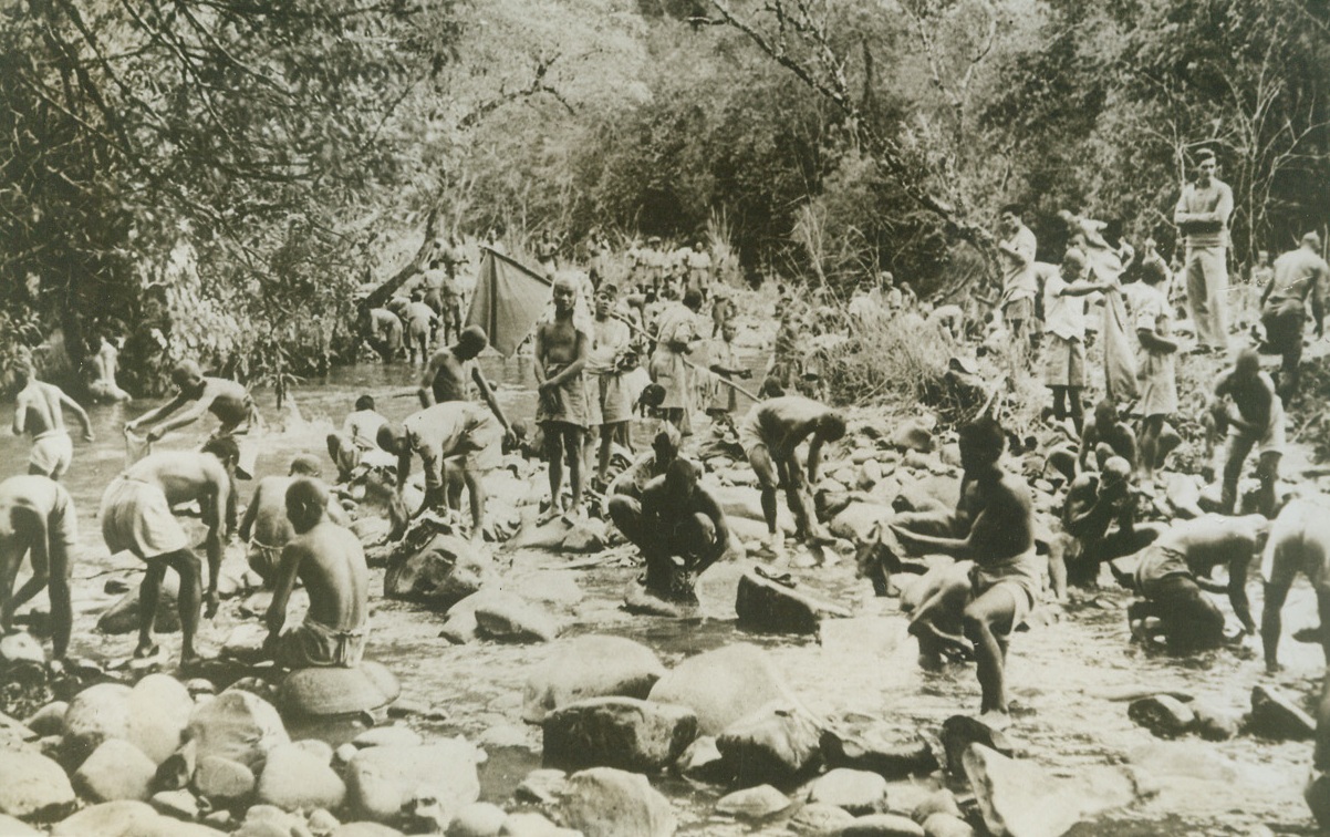 JUNGLE BATH, 5/21/1943. BURMA—Ubduab tribesmen wash the sweat of labor from their bodies and clothing in a rocky jungle stream along the new supply road to Burma. The tribesmen helped Allied troops to cut a supply route through miles of jungle, forests and mountains—which will have to serve the Allies until the Burma road can be reopened. Credit: ACME.;