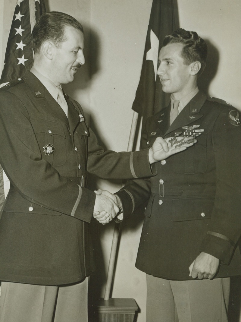 AWARDED THREE MEDALS FOR 100-DAY TREK, 1/18/1944. WASHINGTON, D.C.—A 100-day trek through an enemy-held jungle, after he was shot down by a Jap plane over Rabaul, brought three decorations for Major Arthur L. Post (left) of Milwaukee, Wisc. Bringing back valuable information when he finally reached Yank headquarters, Major Post was cited by Lt. Gen. Kenney and awarded the Distinguished Service Cross, the Flying Cross, and the Air Medal. Here, Brig. Gen. L.S. Kuter, acting Chief of the Air Staff, congratulates the flying hero. Credit Line (ACME);