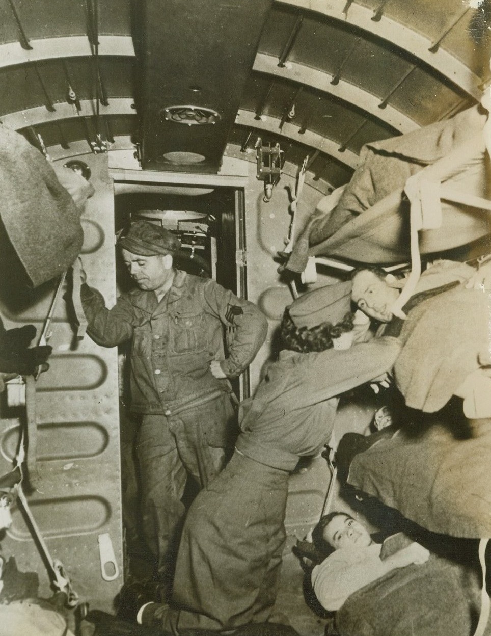 Wounded Flown to U.S. Hospitals, 1/19/1944. Flight Nurse Second Lieut. Kathleen Davis, First Troop Carrier Command, School of Air Evacuation, sees that patients are comfortable in plane during the first mass air evacuation of wounded in the U.S. Flight was from an Eastern port to inland Army general hospitals. The sergeant (standing) is a surgical technician. Credit: Army photo from ACME.;