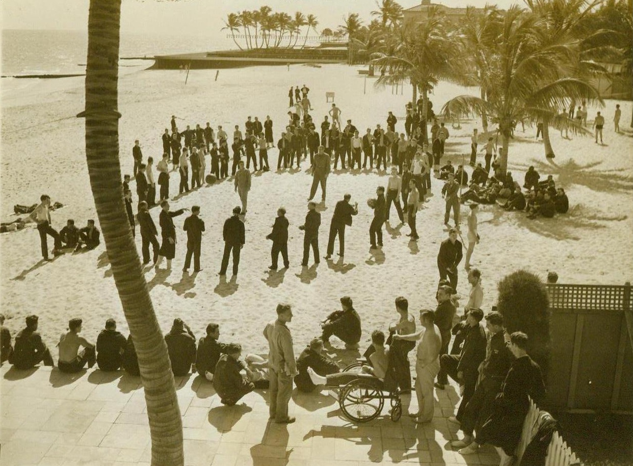 May have to find a new playground, 1/31/1944. PALM BEACH, FLA. – While some soak up sun in wheel chairs and other stretch out on the sand, a group of convalescing soldiers play healthful games on the sand at the Ream General Hospital, onetime Breakers Hotel in Palm Beach. Fighter Buddy Baer, recuperating from a back injury, is in the center of this circle of servicemen who may have to look for another “playground” is the hotel is returned to its owners for commercial use. CREDIT LINE (ACME) 1/31/44;