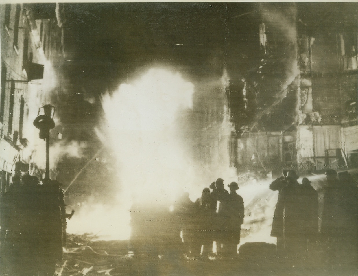 Gas Main Burns After Raid, 2/25/1944. LONDON -- British air raid wardens and fire fighters are silhouetted against the roaring flame of a burning gas main during last night's (Feb. 24th) raid on London by Hitler's bombers. In the background are bombed and burning buildings. Photo radioed to New York today from London. Credit: (ACME Radiophoto);