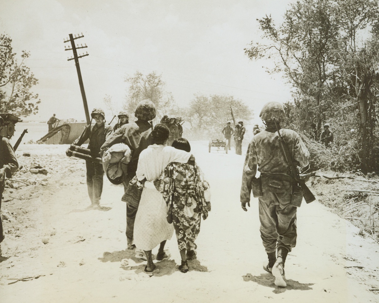 Civilian Prisoners on Saipan, 6/28/1944. Saipan – Japanese mother and daughter, prisoners of war, are escorted to the beach under military escort. Captured on the first day of the invasion of Saipan, these civilian prisoners of war had to wait a full day before prison camps were hastily erected. Credit: ACME;