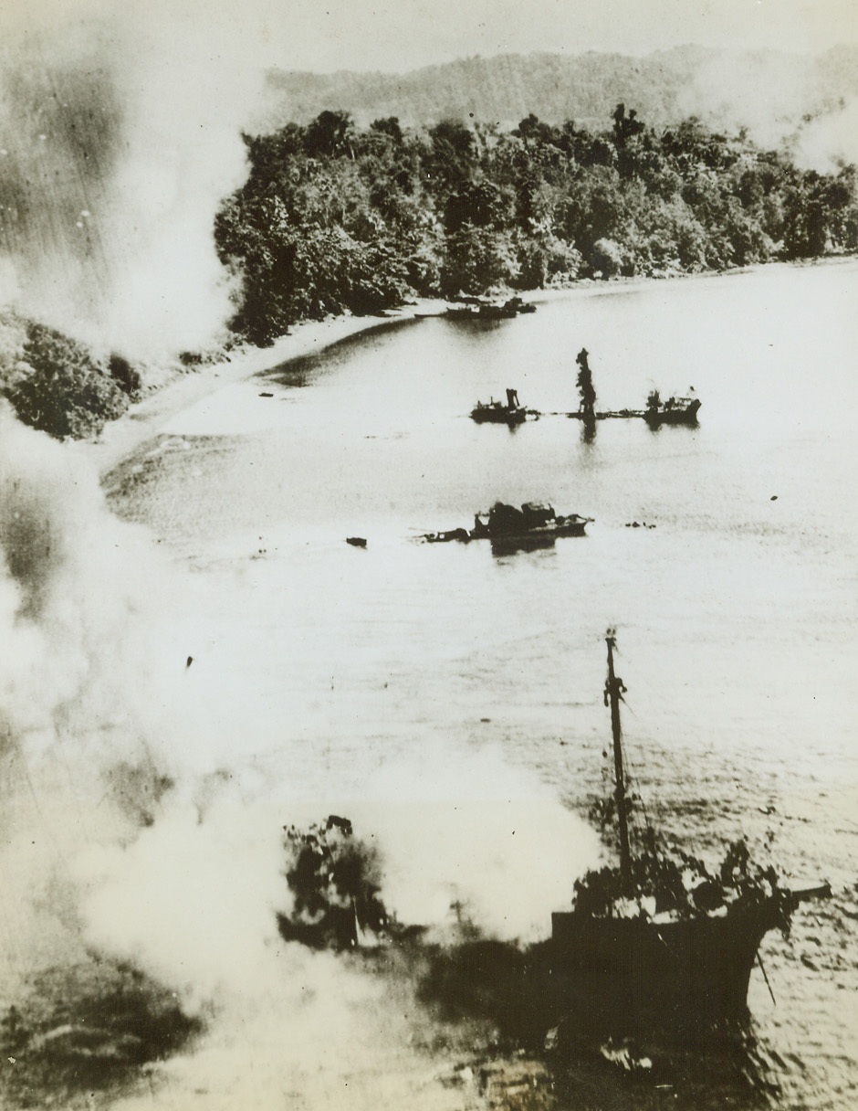 U.S. Bombers Hit at Jap Shipping, 6/27/1944. Manokwari, Dutch New Guinea – Battle smoke from the harbor of Manokwari as US bombers from the 5th Air Force attack Jap shipping.  Strafed from masthead-level, the ship in the foreground is burning fiercely and the two ships in the background are sinking after direct hits.Credit (USAAF photo from ACME);