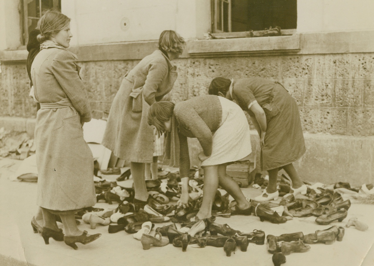 Another Army – Helpless Humanity in Flight, 5/29/1940  Paris, France – Refugees, arrived in Paris, at a clothing distribution center. Fitting is by trial and error. Credit: ACME;